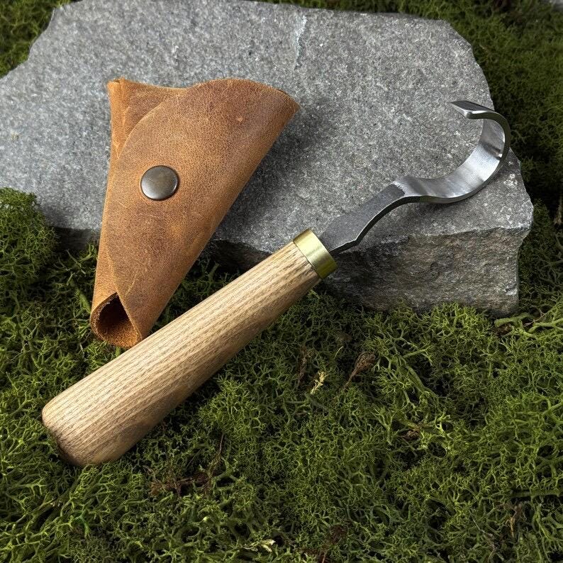A hand-forged carbon steel 52100 tool, suitable for beginners, includes a hook knife with a leather case, a spoon, a bowl and a cup carving