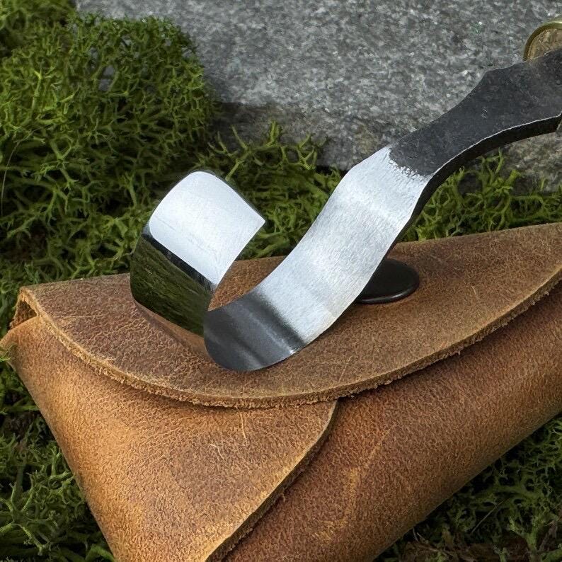 A hand-forged carbon steel 52100 tool, suitable for beginners, includes a hook knife with a leather case, a spoon, a bowl and a cup carving