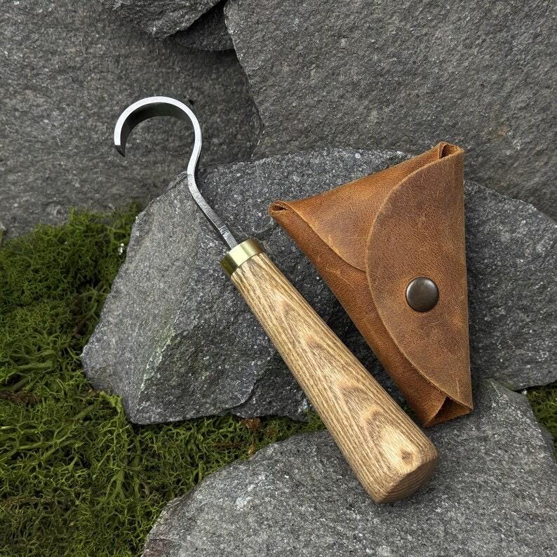 A hand-forged carbon steel 52100 tool, suitable for beginners, includes a hook knife with a leather case, a spoon, a bowl and a cup carving
